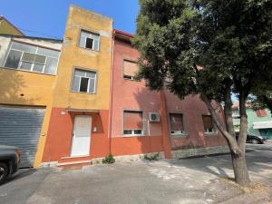 un edificio colorido con un árbol delante en APPARTAMENTO ELEGANTE CARBONIA en Carbonia