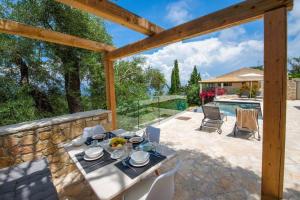 a patio with a table and chairs and a pool at Terra villa by PaxosRetreats in Lákka