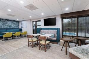 a waiting room with tables and chairs and a flat screen tv at Hampton Inn Perry in Perry