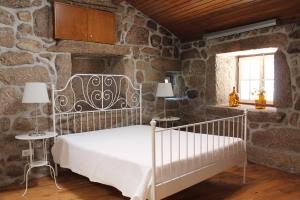 een slaapkamer met een bed en een stenen muur bij Quinta da Mó in Terras de Bouro