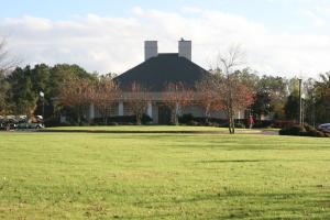 a white building with a black roof with a grass field at Hampton Inn Moss Point in Moss Point