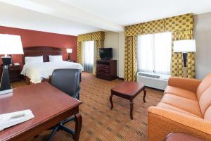a hotel room with a bed and a desk and couch at Hampton Inn Moss Point in Moss Point