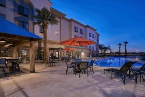 um pátio com mesas e cadeiras ao lado de uma piscina em DoubleTree by Hilton Phoenix-Gilbert em Gilbert