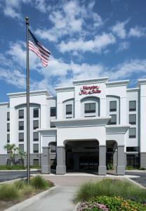 a white building with an american flag in front of it at Hampton Inn & Suites Panama City Beach-Pier Park Area in Panama City Beach