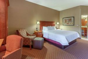 ピオリアにあるHampton Inn East Peoriaのベッドと椅子付きのホテルルーム