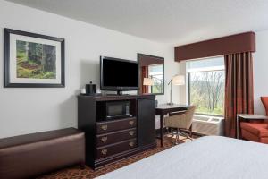 a hotel room with a bed and a desk with a television at Hampton Inn Parkersburg/Mineral Wells in Mineralwells