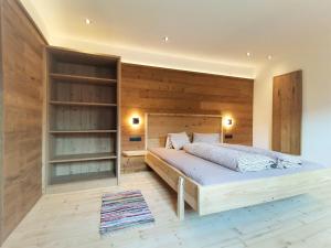 ein Schlafzimmer mit einem Bett und einer Holzwand in der Unterkunft Ferienwohnung 1 "Gilfert" in Fügenberg