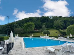 a pool with chairs and umbrellas and a mountain at Le Terrazze: tra laghi e monti in Galbiate