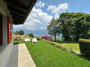 Galbiate的住宿－Le Terrazze: tra laghi e monti，两把白色椅子坐在院子里的草地上