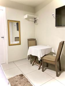 uma sala de jantar com uma mesa, cadeiras e um espelho em Hospedagem Pierina em Gramado