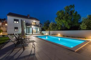 a swimming pool in front of a house at Holiday house Vito Zadar in Zadar