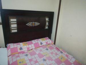 a bed with a pink checkered blanket and a head board at Grand M 