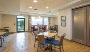 einen Wartebereich mit Tischen und Stühlen sowie ein Esszimmer in der Unterkunft Hampton Inn Freeport/Brunswick in Freeport