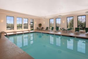 una gran piscina con sillas, mesas y ventanas en Hampton Inn Freeport/Brunswick, en Freeport