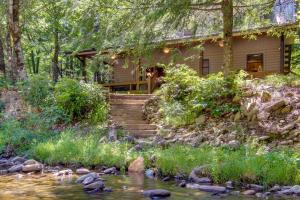 a house in the woods next to a stream at Secluded Rustic Cabin Next to South Toe River! in Busick