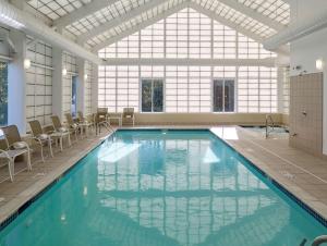 a large swimming pool with chairs and a large window at Hampton Inn Portland-Airport in South Portland