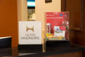 a sign for hilton honors and a box of food on a counter at Hampton Inn Raynham-Taunton in Raynham