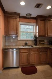 cocina con armarios de madera, fregadero y ventana en Family 3-bedroom home (2nd floor near EWR/Outlet), en Elizabeth
