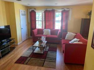 Sala de estar con 2 sofás rojos y mesa de centro en Family 3-bedroom home (2nd floor near EWR/Outlet), en Elizabeth