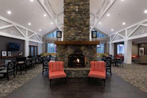 a lobby with a stone fireplace with red chairs at Hampton Inn & Suites Raleigh/Cary I-40 (PNC Arena) in Cary