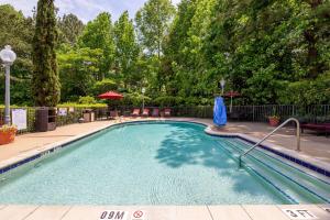 einen Pool in einem Garten mit Bäumen in der Unterkunft Hampton Inn & Suites Raleigh/Cary I-40 (PNC Arena) in Cary