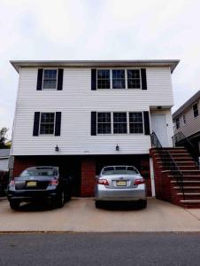 two cars parked in front of a white house at Family 3-bedroom home (2nd floor near EWR/Outlet) in Elizabeth