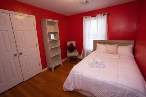 1 dormitorio con paredes rojas y 1 cama con 2 toallas en Family 3-bedroom home (2nd floor near EWR/Outlet), en Elizabeth
