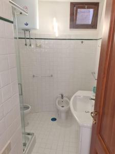 a white bathroom with a toilet and a sink at Un Tuffo nel Blu in Sperlonga
