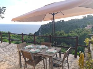 a wooden table with chairs and an umbrella at Un Tuffo nel Blu in Sperlonga