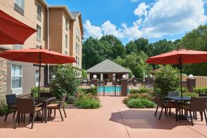 un patio con mesas, sombrillas y una piscina en Hampton Inn & Suites Chapel Hill/Durham en Chapel Hill