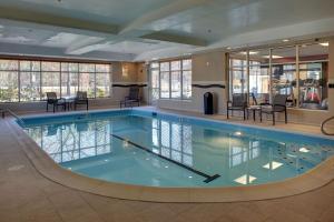 uma grande piscina com cadeiras e mesas num edifício em Hampton Inn Richmond - Airport em Sandston