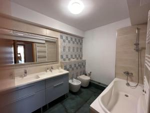 une salle de bain avec deux lavabos et une baignoire et des toilettes dans l'établissement Apartament Sianna, à Mamaia