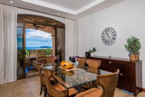 comedor con mesa, sillas y reloj en Jobo 8 Luxury Apartment - Reserva Conchal, en Playa Conchal