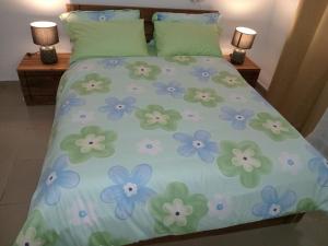 Una cama con flores azules y verdes. en KADIDJA APARTMENTS & SUITES Hedzranawoe, en Lomé
