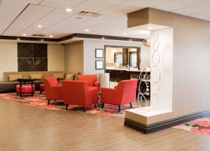 a waiting room with red chairs and a table at Hampton Inn Ridgefield Park in Ridgefield Park