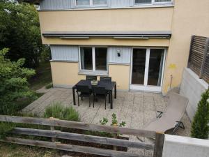 a patio with a table and a chair in front of a house at Apartment Riedwiese in Hörbranz