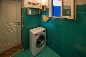 a green tiled bathroom with a washing machine in it at La casa del Geologo in Stromboli