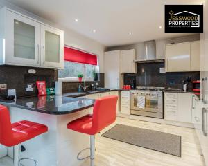 a kitchen with a counter and red chairs in it at Large 6 Bedroom Contractor House by Jesswood Properties ShortLets For Groups, Business And Leisure With Free Parking, Wifi and Pool Table in Luton +24 photos