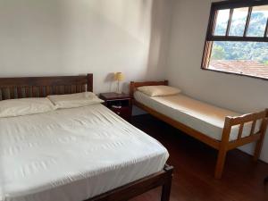 two twin beds in a room with a window at Casa com excelente localização in Campos do Jordão