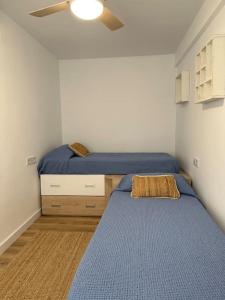 een slaapkamer met 2 bedden en een plafondventilator bij Apartamento a 20 m de playa Almería in Almería