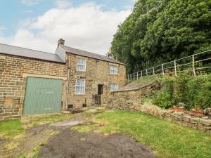 an old brick house with a green garage at Nook Farm Holiday Cottage in Sheffield
