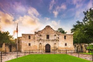 an old stone building with a green lawn in front at The Emily Morgan Hotel - A DoubleTree by Hilton in San Antonio