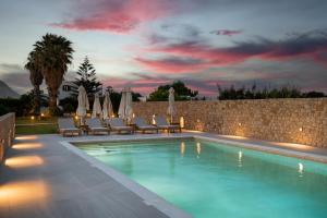 a swimming pool with chairs and umbrellas at night at Agalipa in Skiros