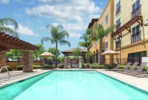 a swimming pool in front of a building with palm trees at Hampton Inn & Suites Lodi in Lodi