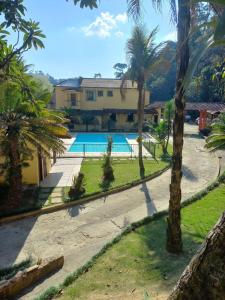 um resort com piscina e palmeiras em Pousada Green Garden em Engenheiro Paulo de Frontin