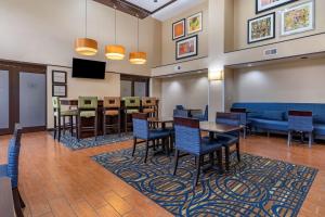Hampton Inn & Suites Louisville East في لويزفيل: غرفة انتظار مع طاولات وكراسي وأريكة
