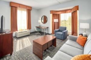 sala de estar con sofá, TV y escritorio en Hampton Inn Louisville Northeast, en Louisville