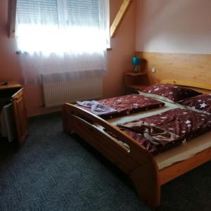 1 dormitorio con cama grande de madera y ventana en Malom Fogadó, en Balatonboglár