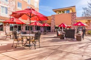 a patio with tables and chairs and red umbrellas at Hilton Garden Inn St. George in St. George