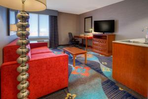 Habitación de hotel con sofá rojo y cocina con fregadero en Hampton Inn Milpitas, en Milpitas